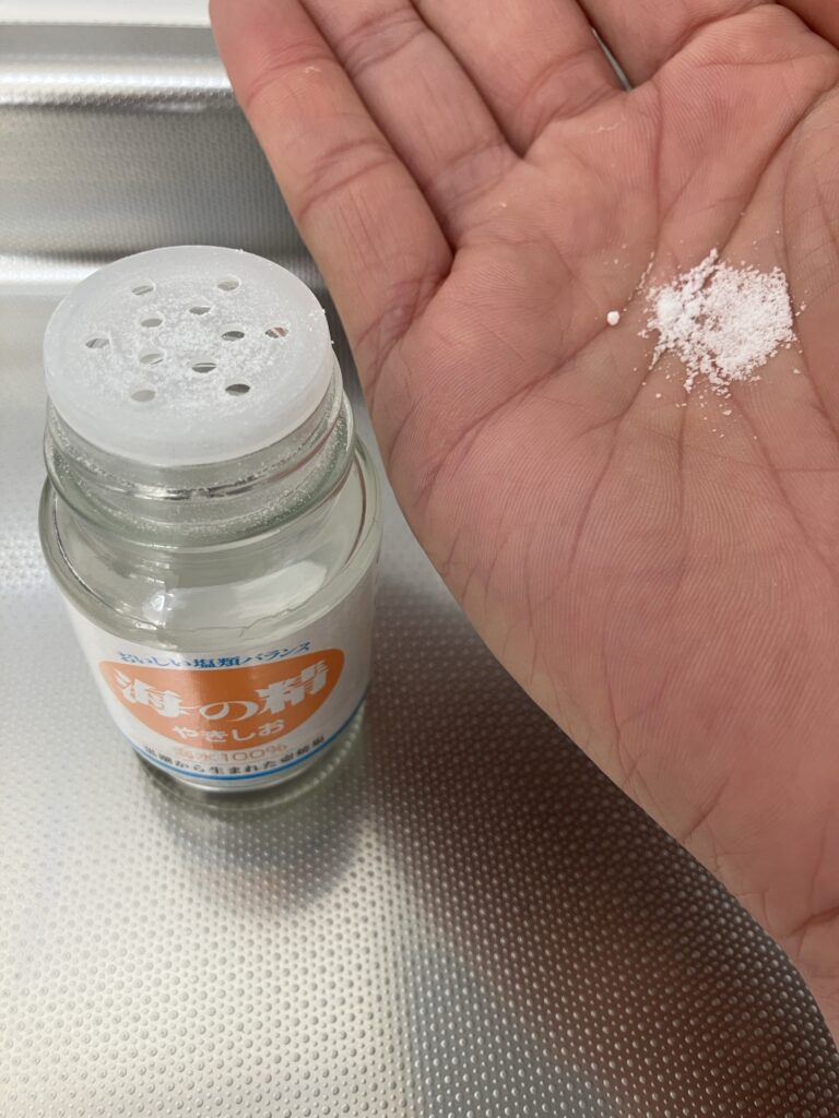 海の精 やきしおを手のひらに乗せて粒の細かさとサラサラ感を確認している様子