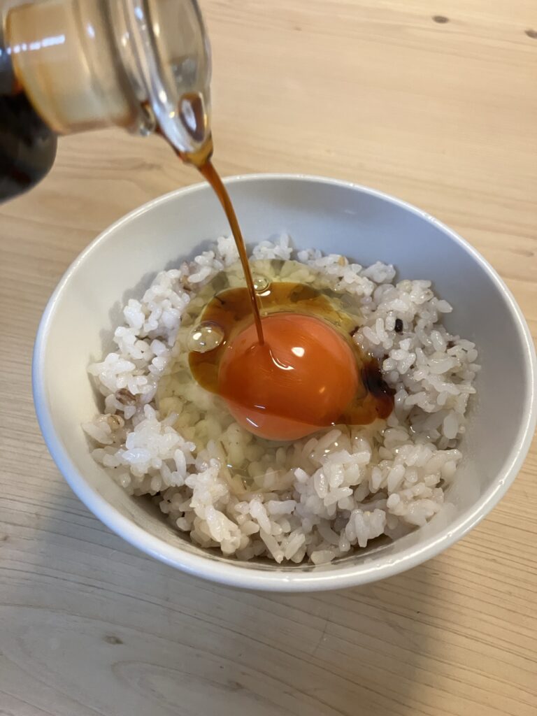 卵かけご飯に足立醸造の国産有機醤油をかけている様子
