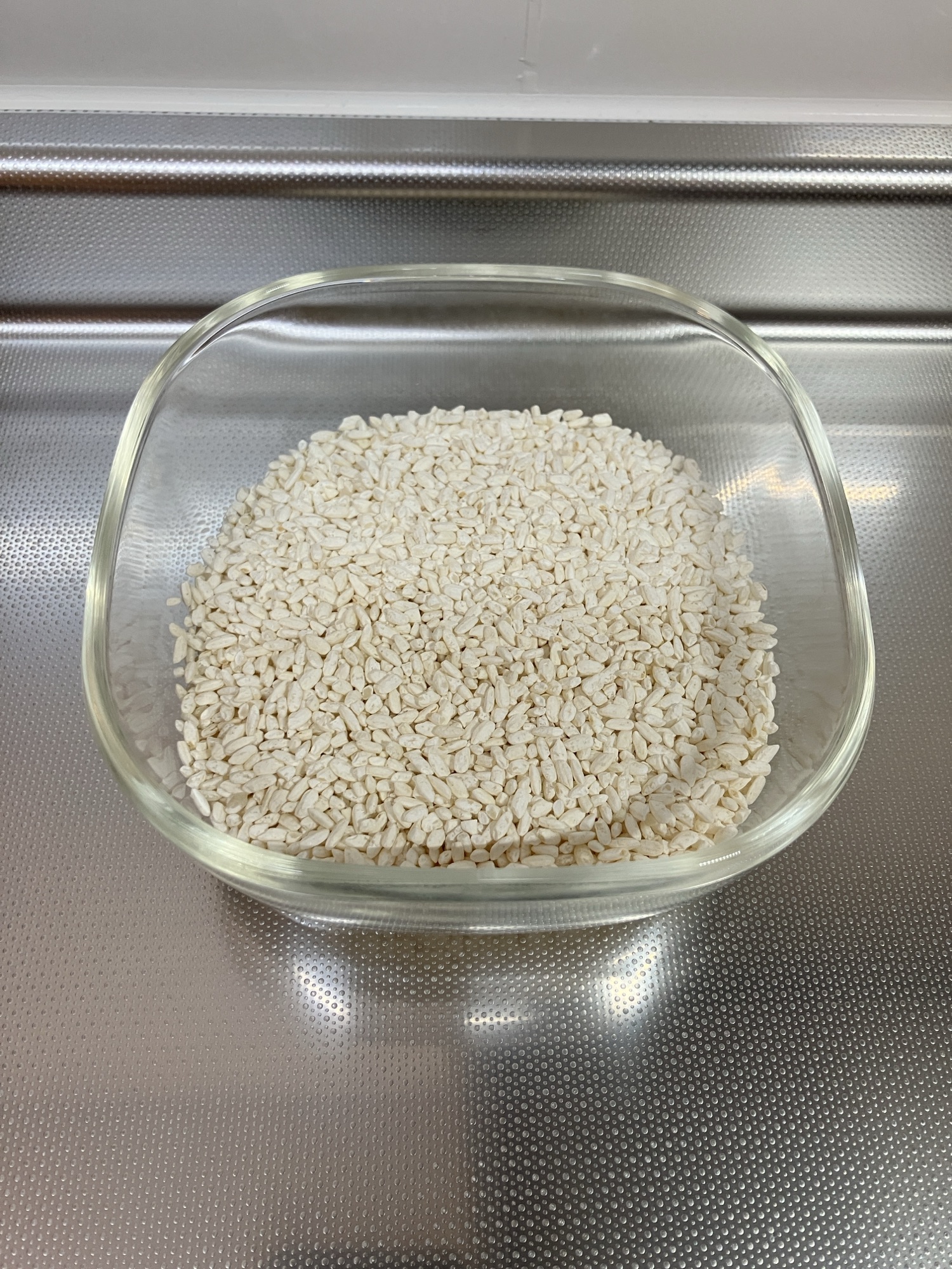 ガラス容器に入った乾燥米こうじの粒。白くふっくらとした粒状の乾燥こうじ