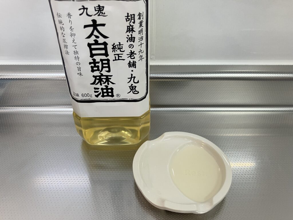 九鬼太白純正胡麻油のパッケージと透明で色・香りのない油を小皿に注いだ様子