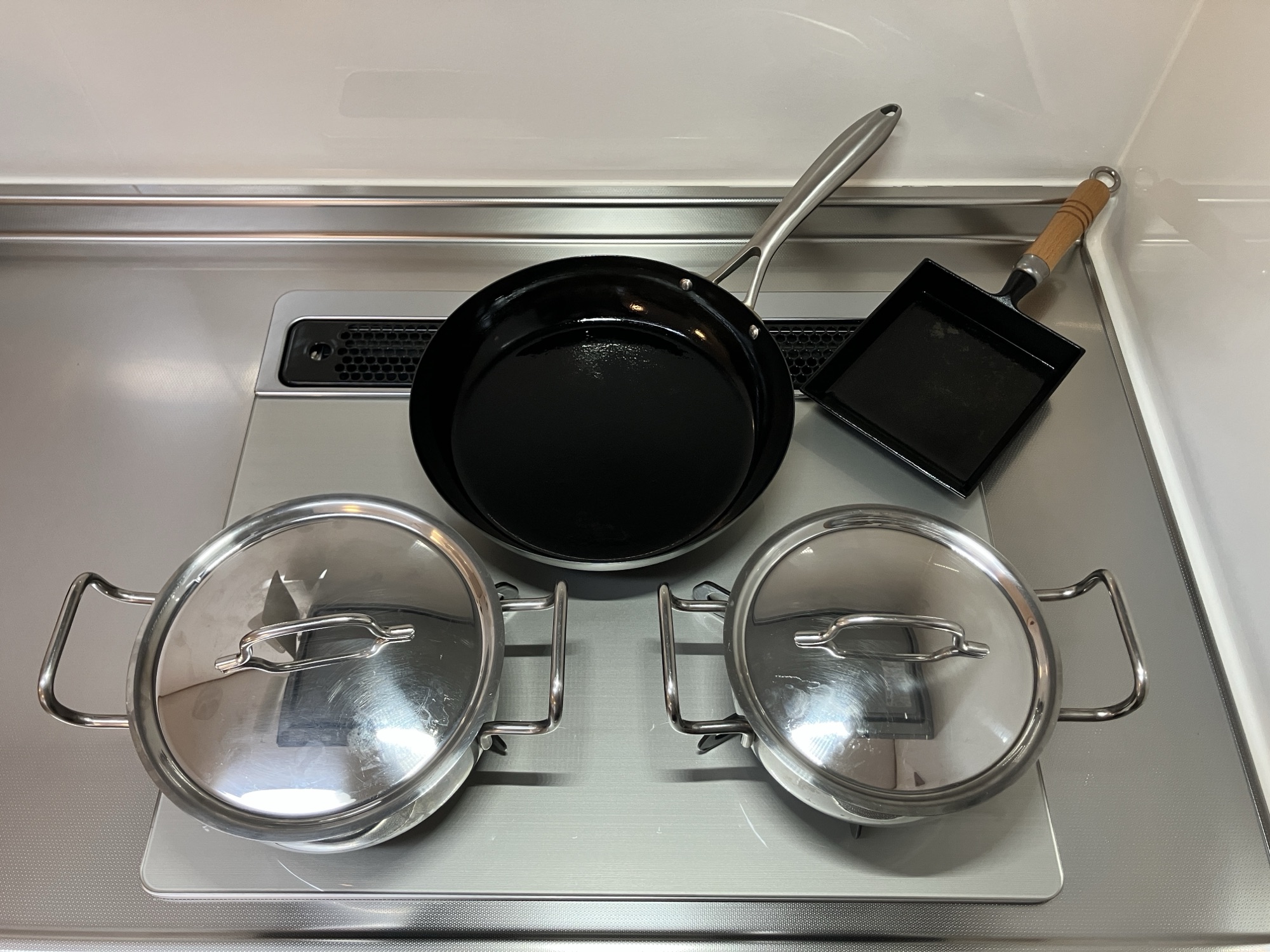 ガスコンロの上に並べた日本製調理器具4点。黒いフライパン、玉子焼き器、ステンレス蓋付き鍋2つ