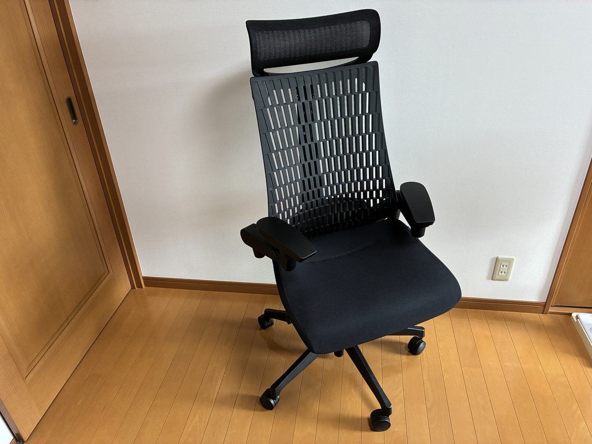 イトーキ アクトチェア KG427JEE ブラックの全体を正面斜めから見た様子。エクストラハイバックのヘッドレストとエラストマー背が見える