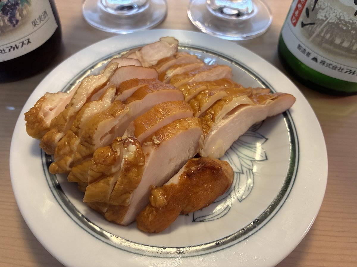 薄切りにしたサイトウハムのスモークチキンを皿に盛りワインと合わせたところ